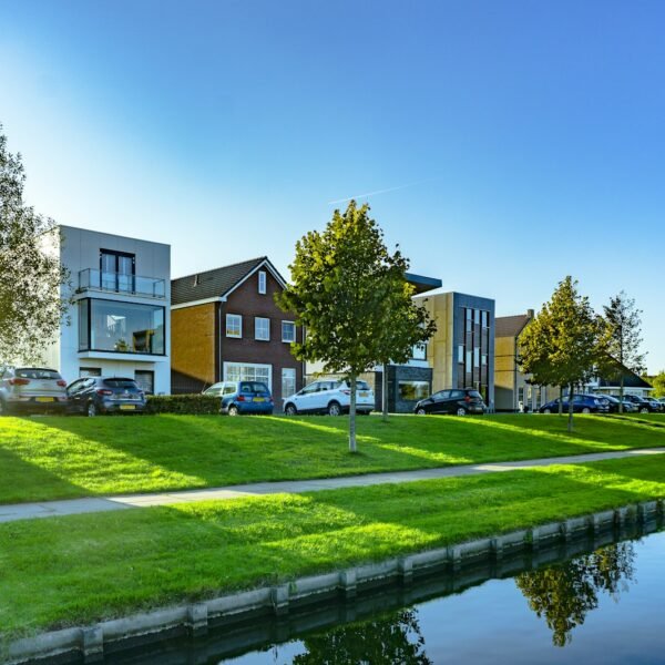 white and brown house near green grass field and body of water during daytime